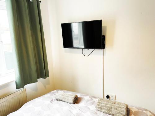 a room with a bed with a tv on the wall at Brixton/Oval House in London