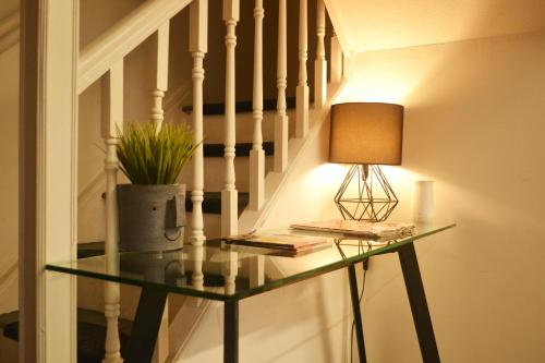a lamp on a glass table next to a staircase at Brixton/Oval House in London
