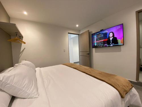 a bedroom with a bed with a flat screen tv on the wall at 96K Premium Suite - Habitaciones a minutos del Aeropuerto en Bogotá in Bogotá