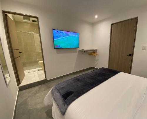 a bedroom with a bed and a television on the wall at 96K Premium Suite - Habitaciones a minutos del Aeropuerto en Bogotá in Bogotá