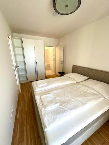 a large white bed in a room with wooden floors at COHO City Apartments mit hauseigener Tiefgarage in Vienna
