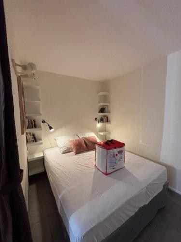 Cette chambre comprend un lit blanc avec une boîte. dans l'établissement A deux pas des thermes et de l'étang de Thau, à Balaruc-les-Bains