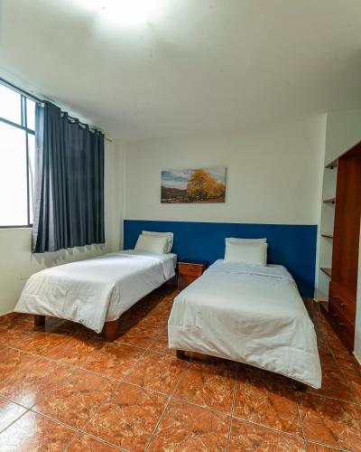 two beds in a room with blue and white walls at Hospedaje Gran Imperial in Tumbes
