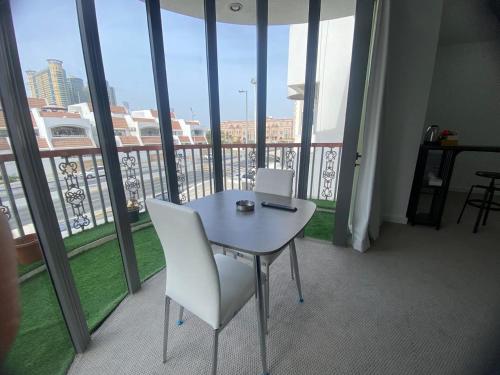 a table and chairs in a room with a large window at Dinar - cozy master bedroom in Abu Dhabi