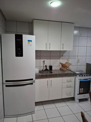 a kitchen with white cabinets and a white refrigerator at Apartamento aconchegante in Teresina