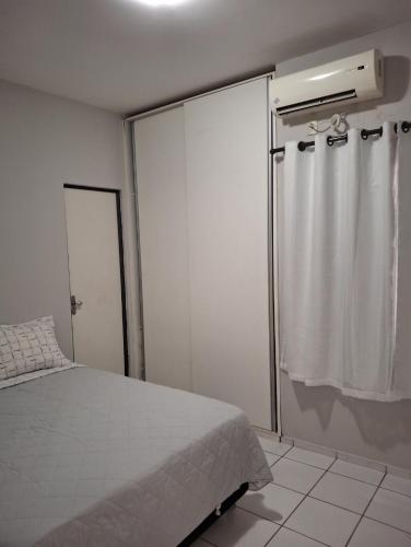 a bedroom with a white bed and a shower at Apartamento aconchegante in Teresina