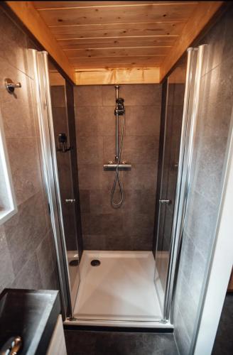 a shower with a glass door in a bathroom at Tiny House Mayu - Veluwe Airco 4 persons in Arnhem