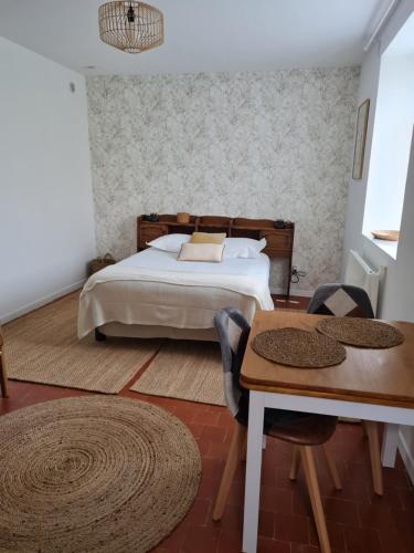 a bedroom with a bed and a wooden table at Le Moulin de serres in Bazoches
