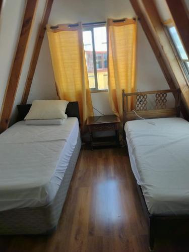 two beds in a room with two windows at Casa Playa Loreto, familiar, ubicada a 120 metros de la playa, con maravillosa vista al mar, cercano a Caldera in Caldera