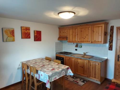 a kitchen with wooden cabinets and a table with chairs at CAV MES VALLEES Torgnon Vda in Torgnon