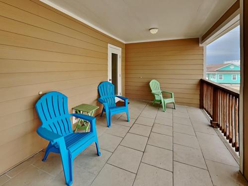 a porch with two blue chairs and a table at Forever in Flip Flops in Port Aransas