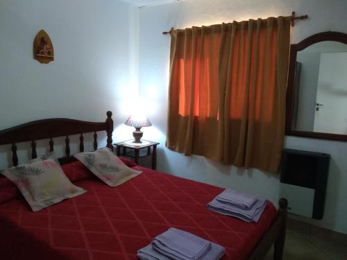 una camera da letto con un letto con lenzuola rosse e una finestra di Alojamiento Corcovado a El Corcovado