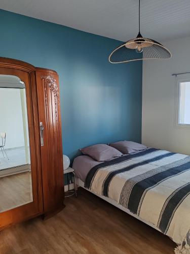 une chambre avec un lit et un mur bleu dans l'établissement Maison à 10 min de la plage, à Les Sables-dʼOlonne