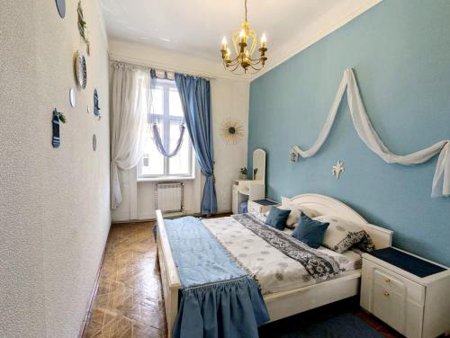 Un dormitorio con una cama con paredes azules y una lámpara de araña. en Ratusha Apartments, en Leópolis