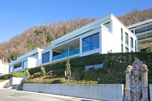 a white building with a hill in the background at Residenza La Fontana - Happy Rentals in Bissone