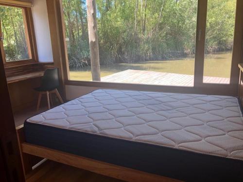 a bed in a room with a large window at Casa flotante en el delta, tigre in Ingeniero Maschwitz