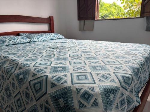 a bed with a blue and white quilt on it at Pousada Recanto do Japa in Nilo Peçanha