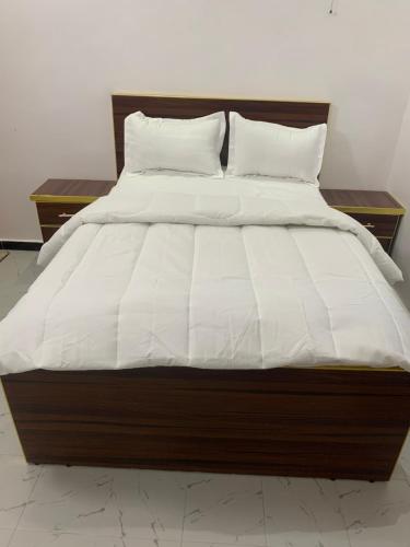 a large bed with white sheets and pillows at Appartement meublé saint louis - Bango in Dakar Bango