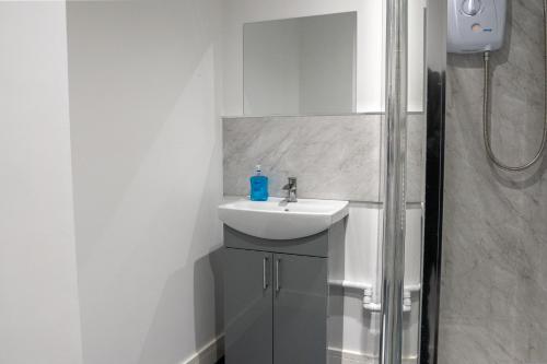 a white bathroom with a sink and a shower at Juniper Berry Apartments in Southampton