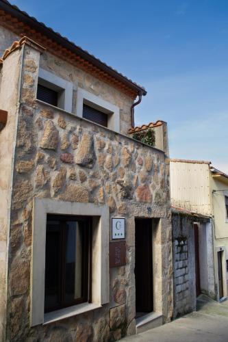 an old stone building with two windows on a street at Casa Rural Doña Sol in Montánchez
