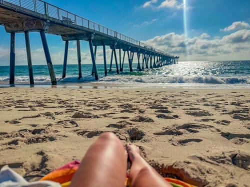 a person sitting on the beach near a pier at ITH Hermosa Beach Surf Hostel LAX in Hermosa Beach
