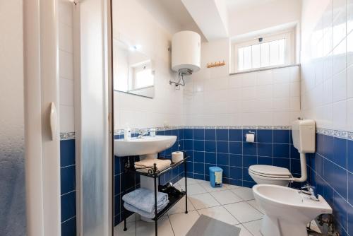 a blue and white bathroom with a toilet and a sink at Case Vacanza Alega Mare in Nizza di Sicilia