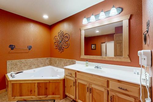 a bathroom with a tub and a sink and a mirror at Lost Creek Haven in Branson West