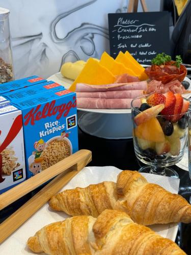 a table topped with pastries and a bowl of fruit at Birdies Townhouse Mitchelstown in Mitchelstown
