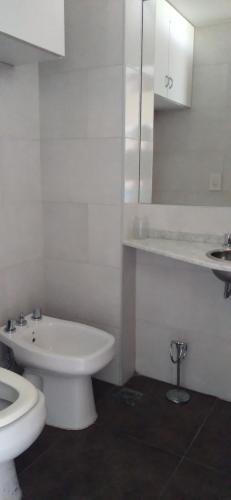 a white bathroom with a toilet and a sink at Terrazas de la Colina in Victoria