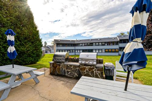 two picnic tables with umbrellas in front of a building at Unit 117 for Poolside Fun in Wells