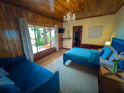 a living room with blue furniture and a chandelier at Hotel Poas Paradise in Alajuela City