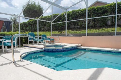a swimming pool with blue chairs next to a building at Super Mario Hideaway - Pool, Spa, Game Room Fun! in Davenport