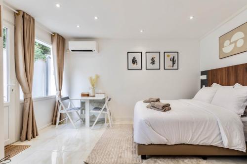 ein weißes Schlafzimmer mit einem Bett und einem Schreibtisch in der Unterkunft Studio Cosy et Calme - 35 min de Paris centre in Romainville