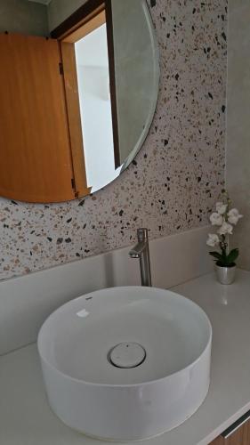 a white sink in a bathroom with a mirror at Suíte tripla com vista piscina em casa familiar de luxo em Itaipu in Niterói