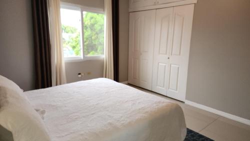 a bedroom with a white bed and a window at Central Upscale New Kingston Apt with pool in Kingston