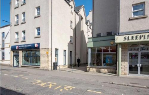 an empty street next to a building with shops at Ness Central in Inverness