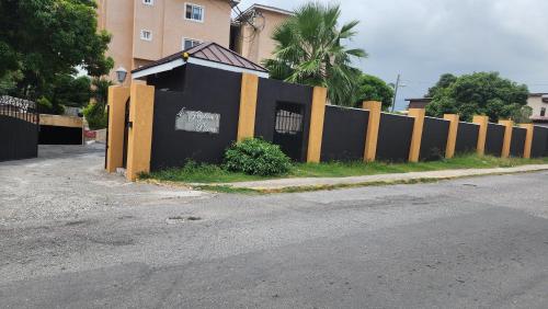a black and yellow fence next to a street at Central Upscale New Kingston Apt with pool in Kingston
