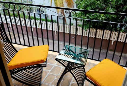 two chairs and a glass table on a balcony at Central Upscale New Kingston Apt with pool in Kingston