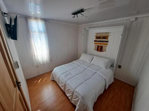 a small bedroom with a white bed in it at Habitación cocina y Quincho con Piscina temperada in Lenca