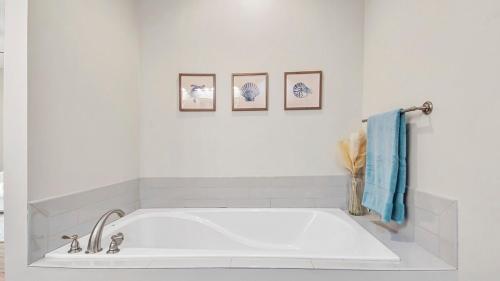 una vasca bianca in bagno con tre immagini sul muro di Guilty Treasure a Panama City Beach