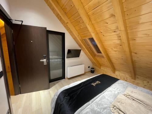 a room with a bed and a wooden ceiling at PineHill Hotel, Restaurant , Pool & Spa - RAZEM in Razëm
