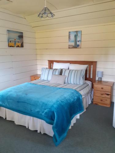 a bedroom with a large bed with a blue blanket at India House & Ica Whare in Whareama, Nr Riversdale Beach in Whareama