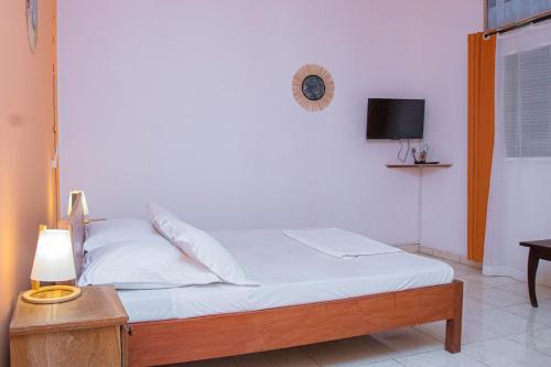 - une chambre avec un lit avec des draps blancs et une table dans l'établissement Espace Kaled, à Diego Suarez