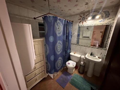 a bathroom with a blue shower curtain and a toilet at Casa Isis in Constitución