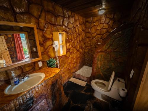 a stone bathroom with a sink and a toilet at Hotel Poas Paradise in Alajuela City