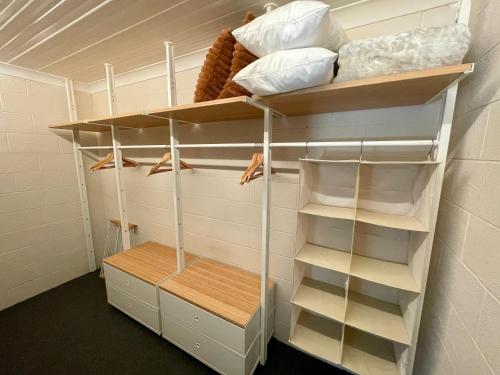 a walk in closet with white shelving and shelves at White Rabbit Mountain Guest House in Mount Beauty