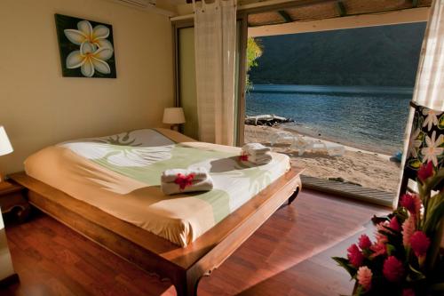 a bedroom with a bed with a view of the water at Robinson's Cove Villas - Deluxe Cook Villa in Papetoai