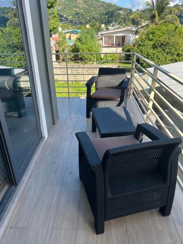 Dos sillas y una mesa en un balcón con vista. en Queens Court Apt 1B, en Puerto España