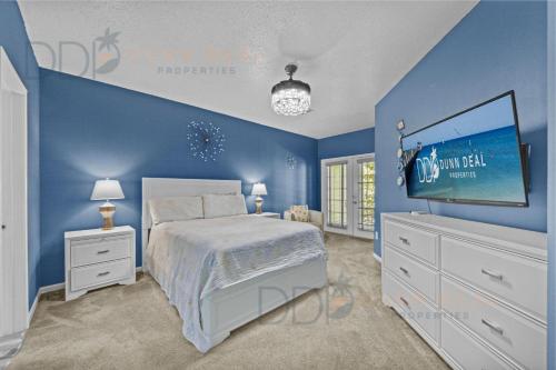 1 dormitorio azul con 1 cama y TV en Legacy Villa 1506, en Gulfport