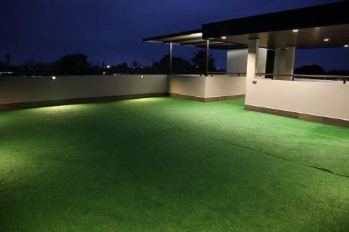 a green lawn with lights on the side of a building at Hotel 1140 in Linares